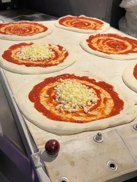Deegbodems met tomatensaus en kaas, klaar voor de oven